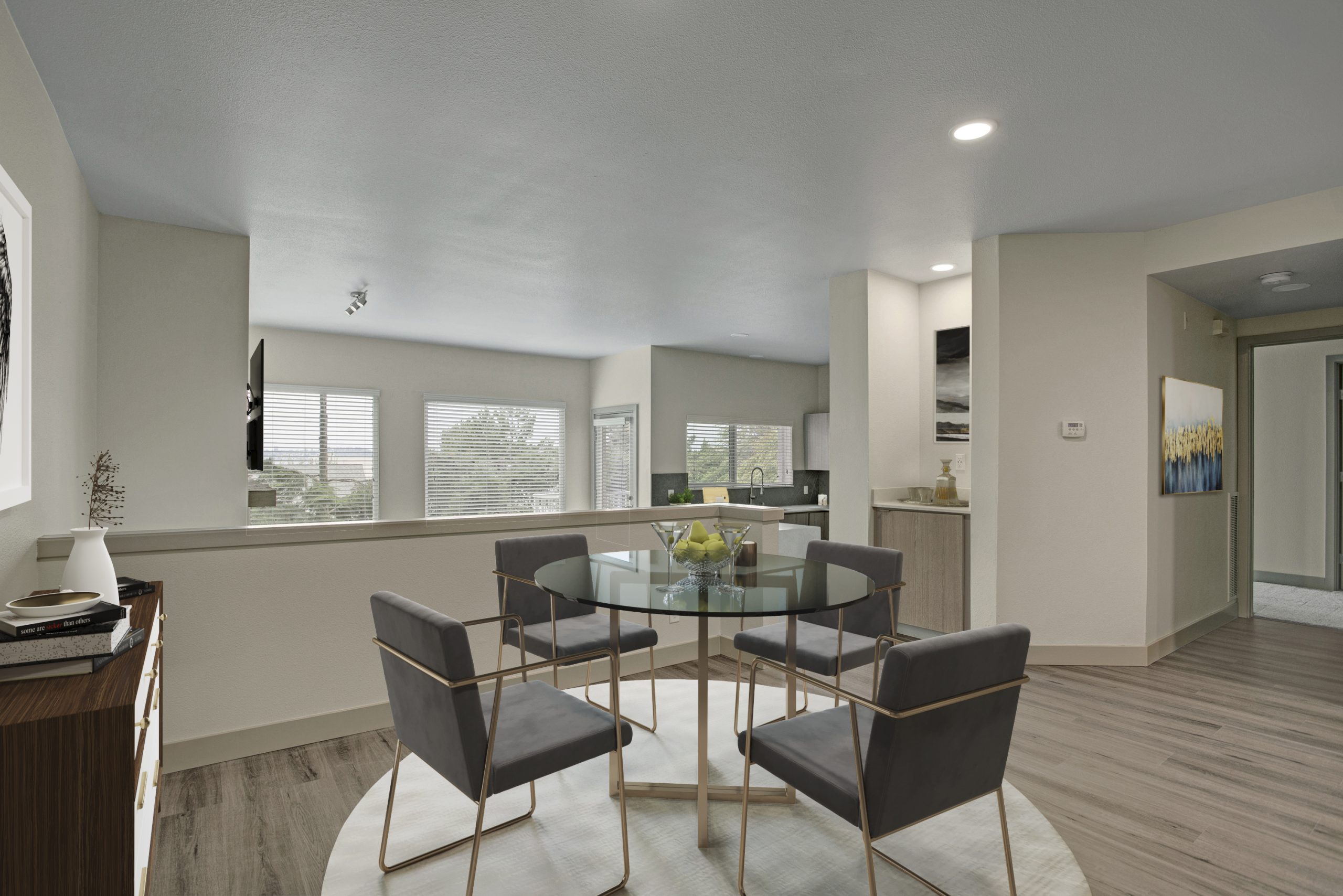 Modern apartment dining area with glass dining table, upholstered chairs, and open kitchen