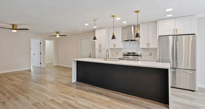 Modern kitchen interior with a large island, white cabinets, stainless steel appliances, and pendant lighting