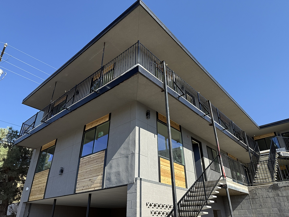 Modern multifamily residential building with balconies, exterior staircases, and wood and concrete exterior finishes