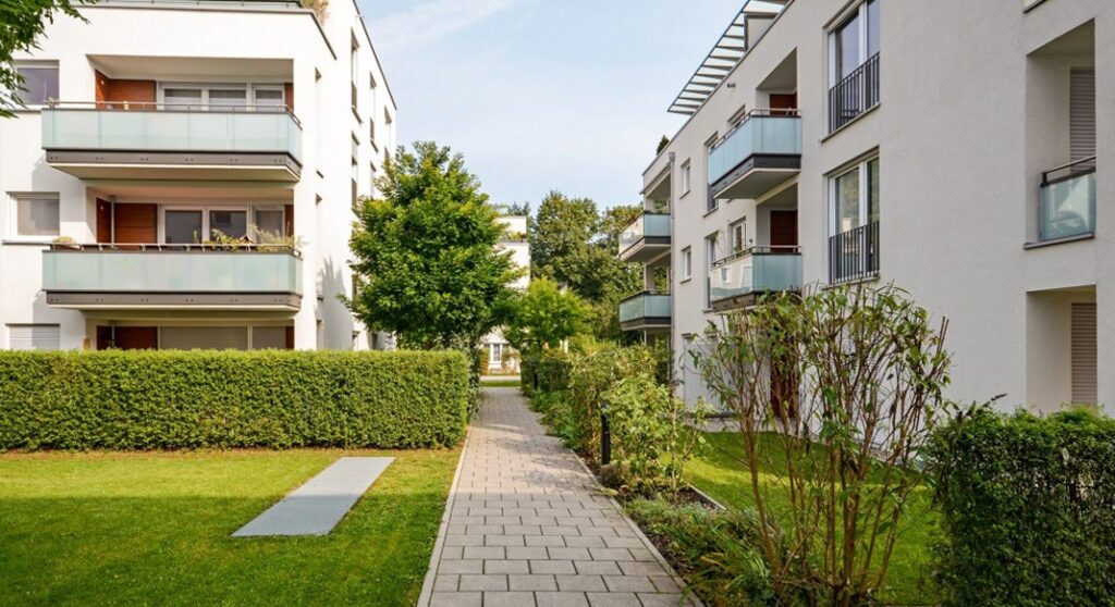 Modern residential landscaping featuring green hedges along a paved walkway